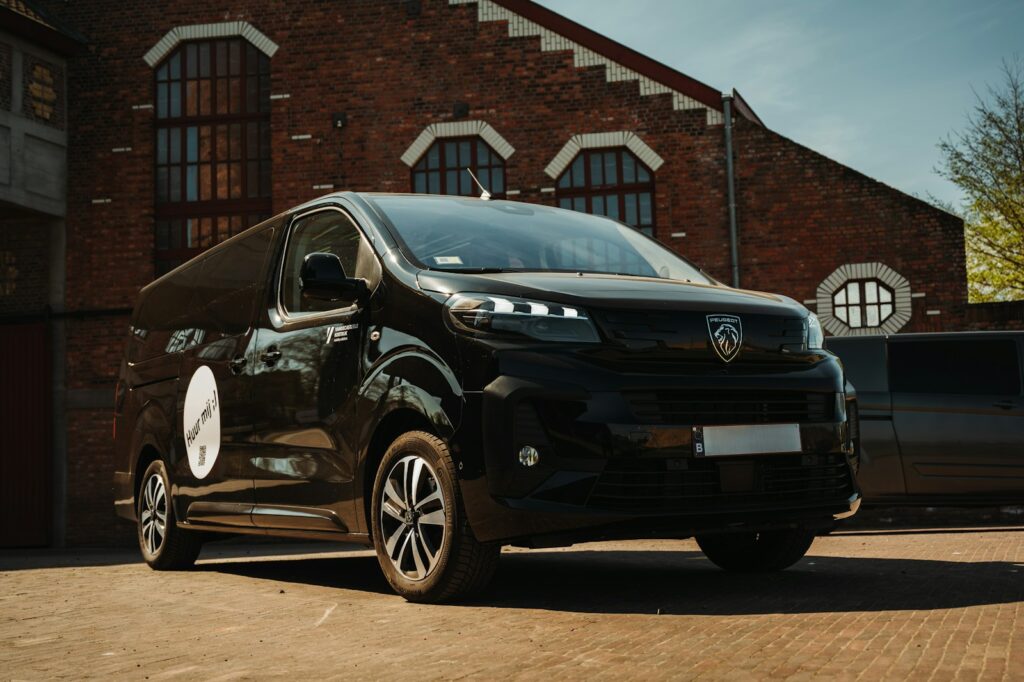 A black van parked in front of a brick building.